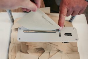 Poll - Person holding white machine on top of white table